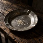 Um prato de alumínio amassado sobre uma mesa rústica com poucos grãos de alimento, simbolizando a insegurança alimentar e a fome.